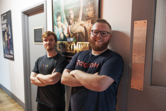 Two of the GURTmania cast standing in front of the show poster